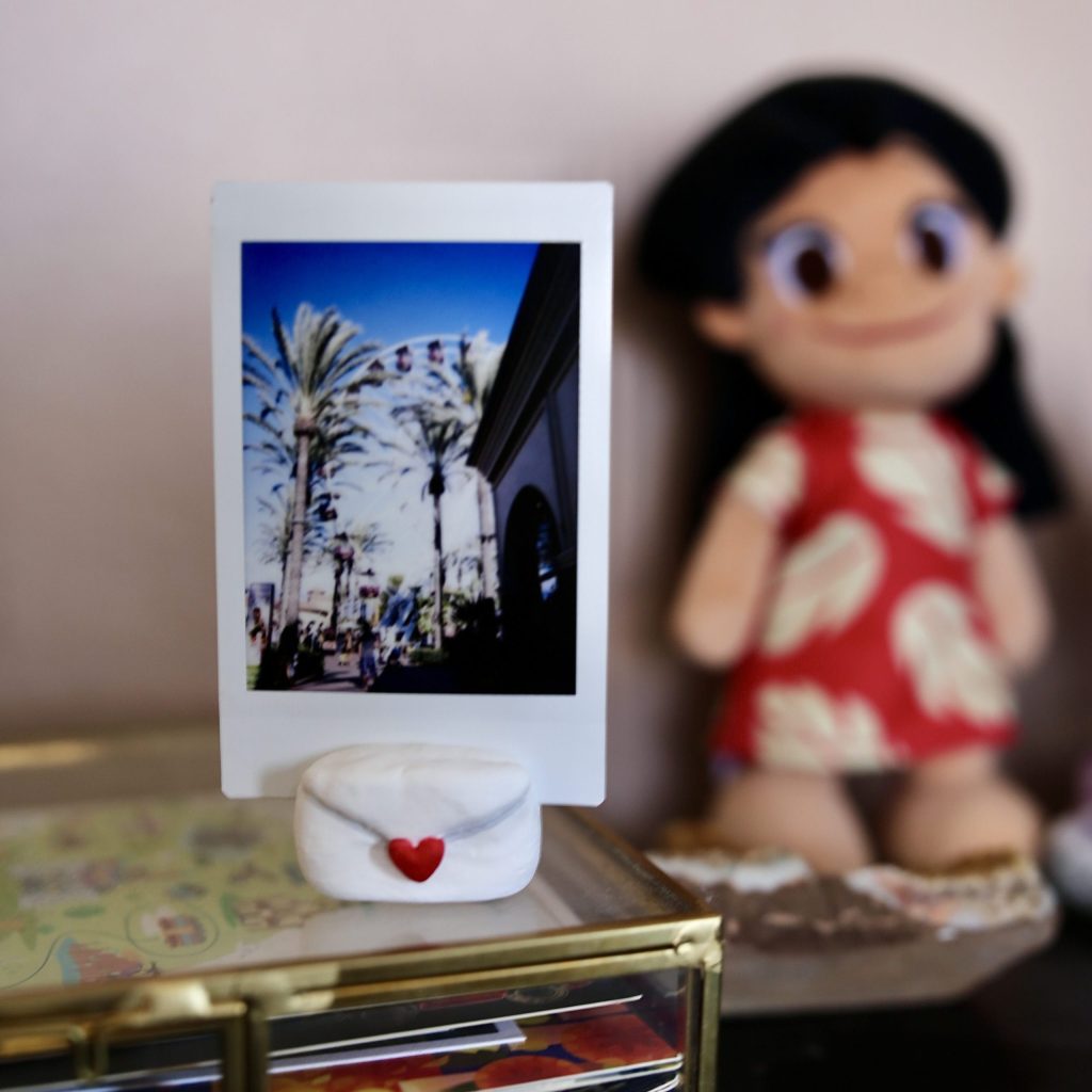 Air-dry clay photo stand in the shape of an envelope holding a polaroid photo