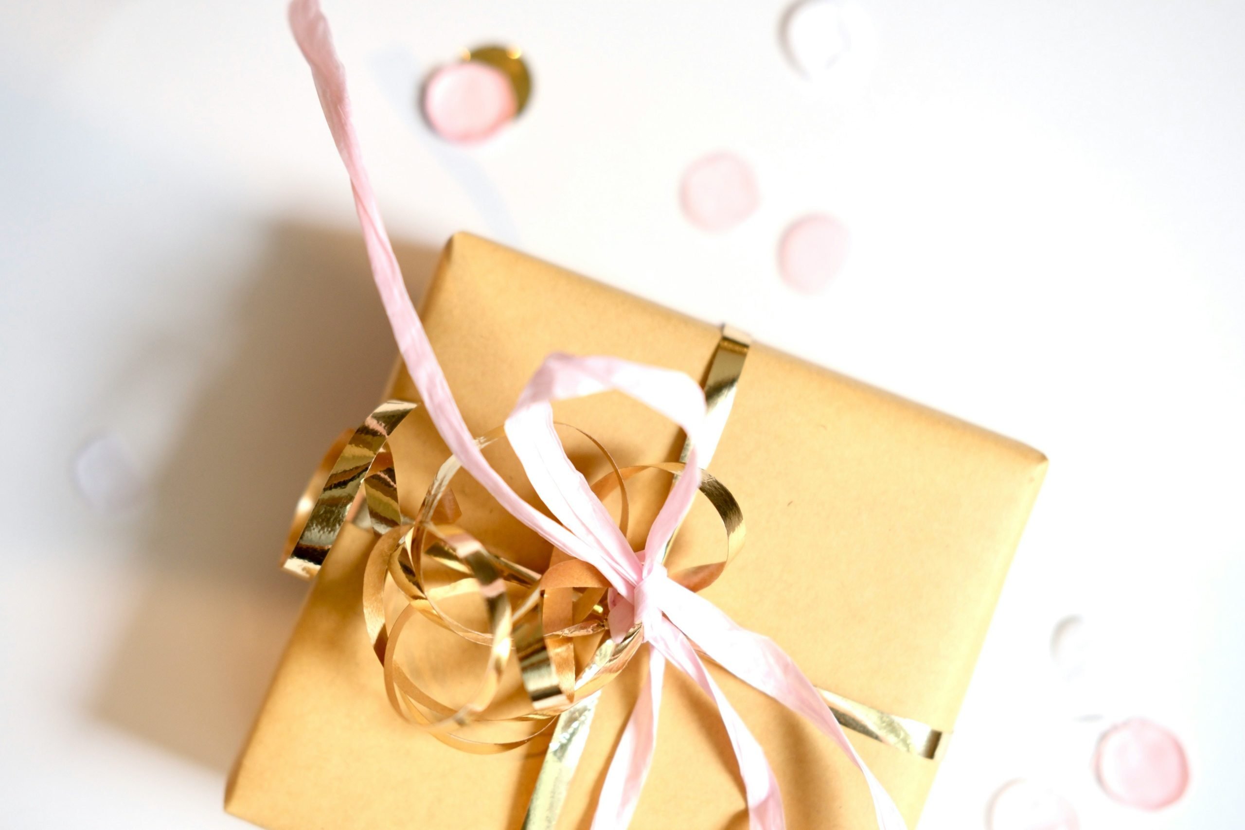 tan gift box with gold and pink ribbon