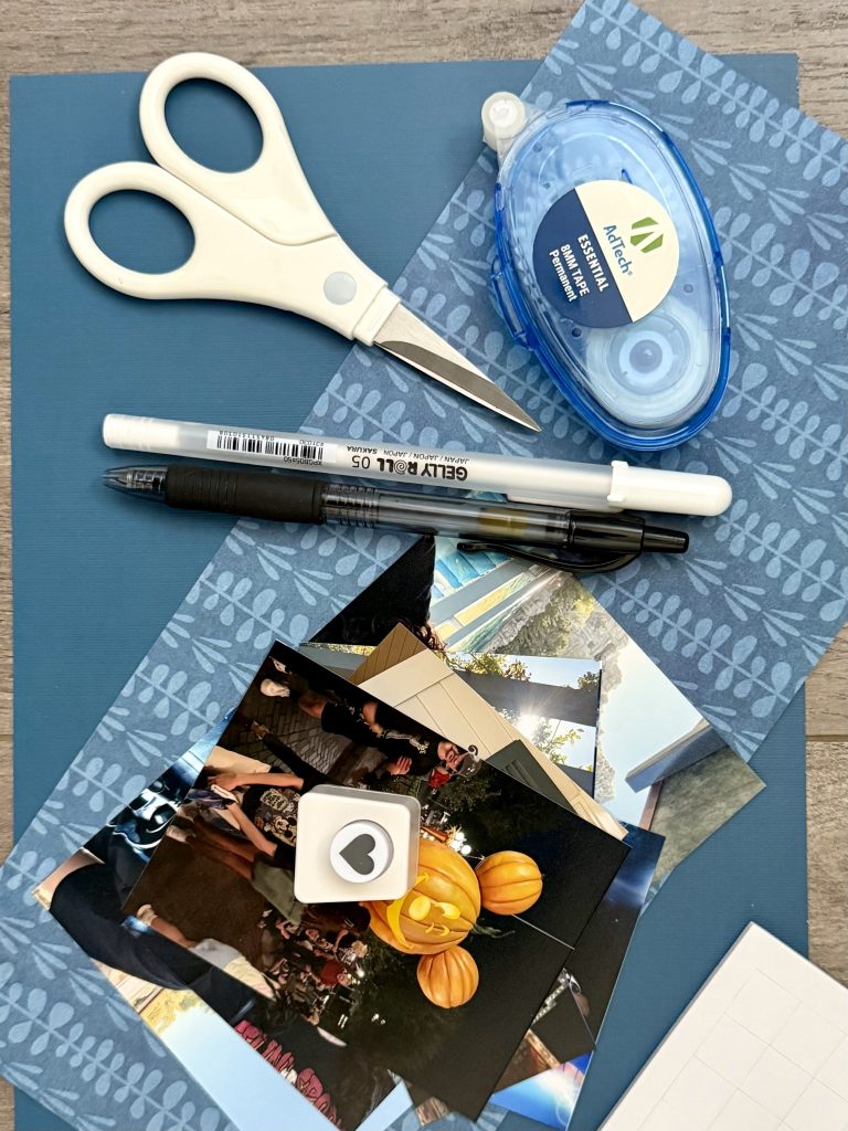 blue scrapbook paper, scissors, photos, and pens