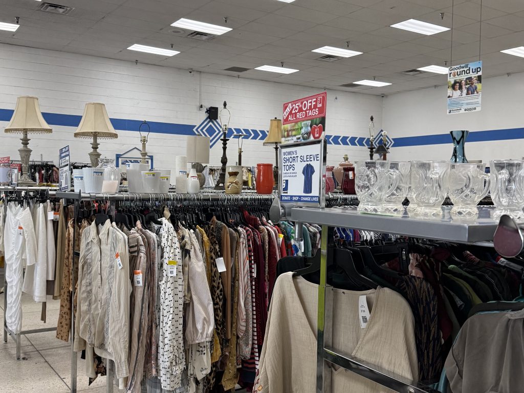 thrift store clothing racks with lamps and vases