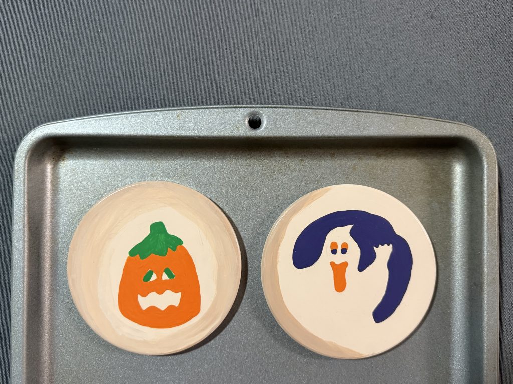 ceramic coasters painted like halloween pillsbury sugar cookies on baking sheet